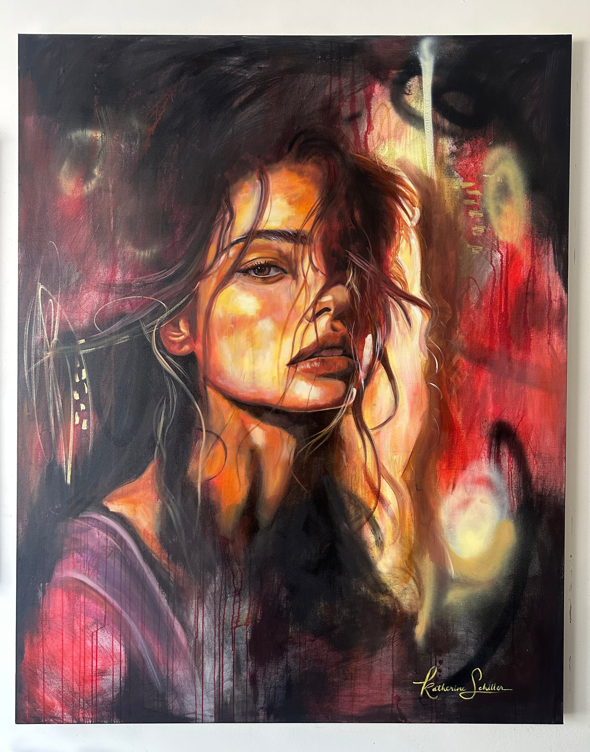 An expressive portrait painting of a woman with dark hair and glowing warm highlights, rendered in black, red, orange, and purple tones. The artwork fills most of the frame and appears mounted against a light wall.